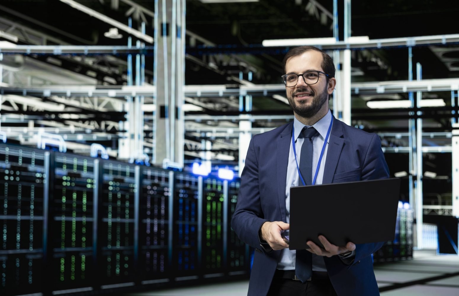 Smiling data center engineer using laptop to evaluate infrastructure diagnostic reports, pleased by results. Happy server hub employee satisfied by automated supercomputers processing