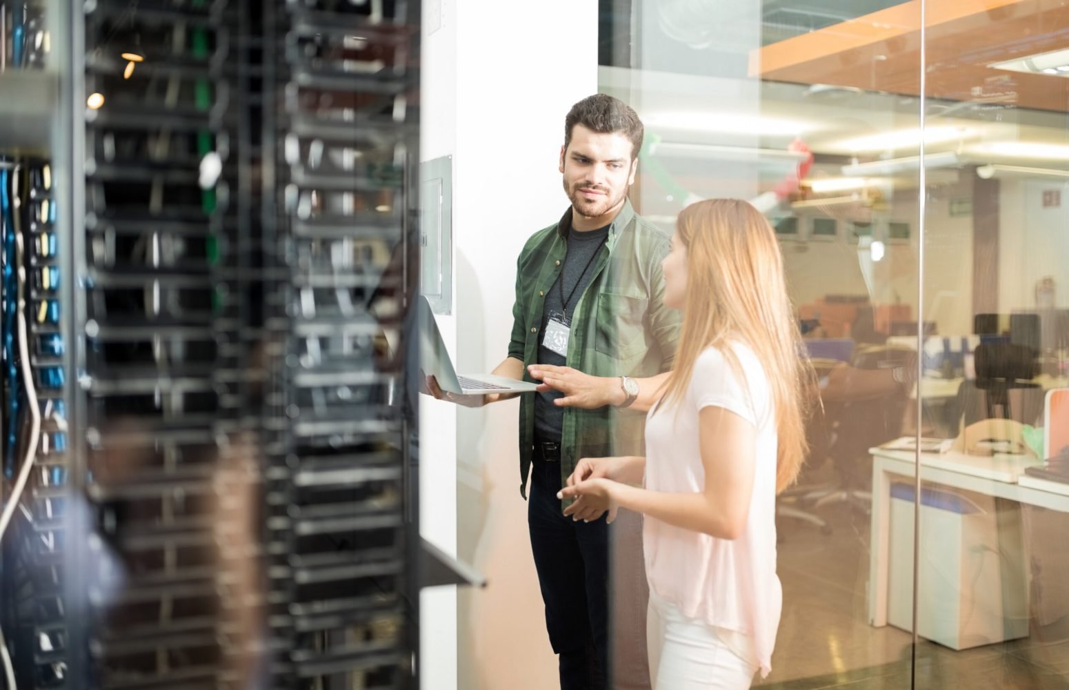 Two business people standing in server room with laptop and discussing